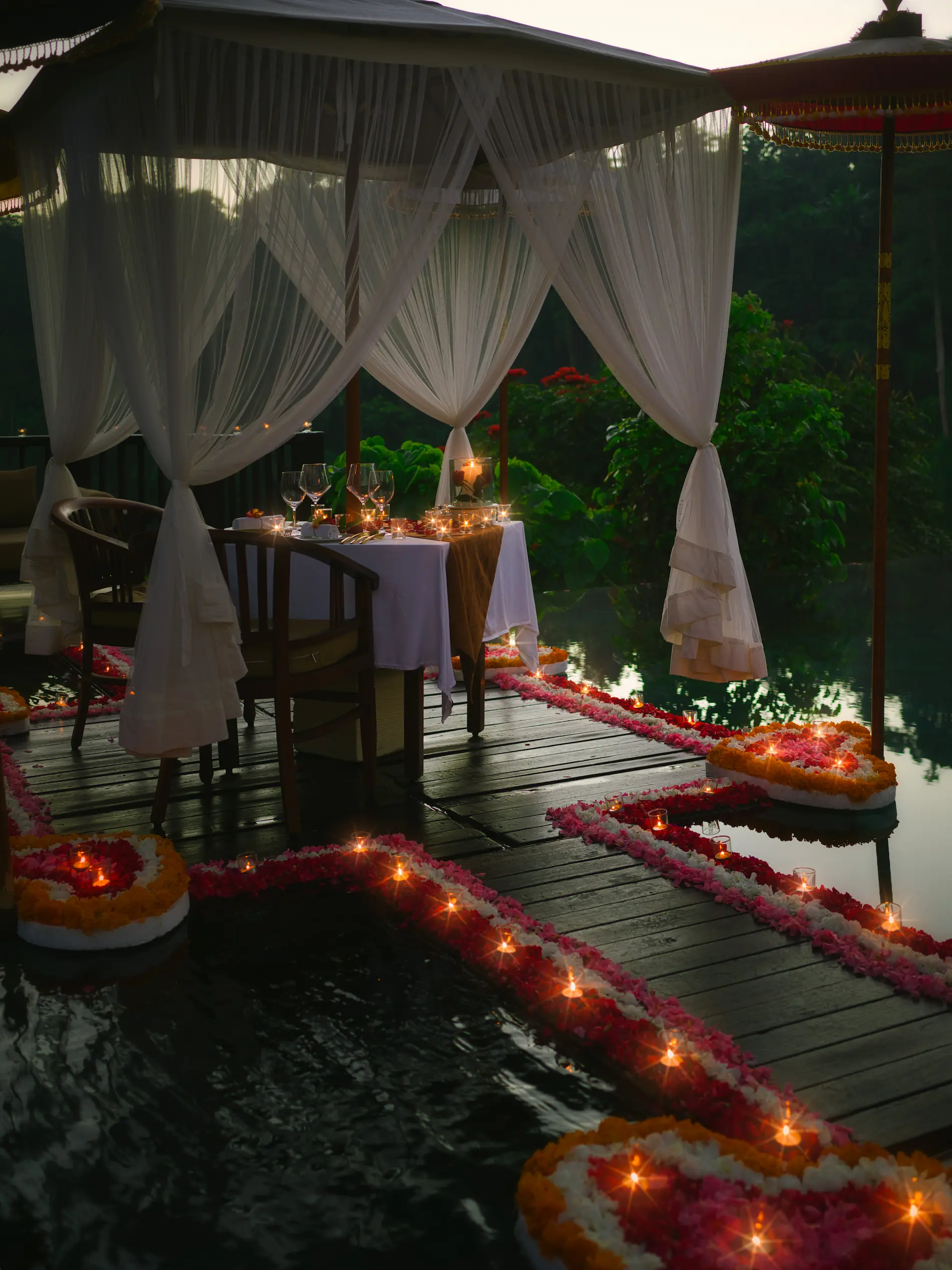 Exclusive floating dinner in Bali at Hanging Gardens Ubud, luxury candlelit table on award-winning infinity pool with flower decorations.