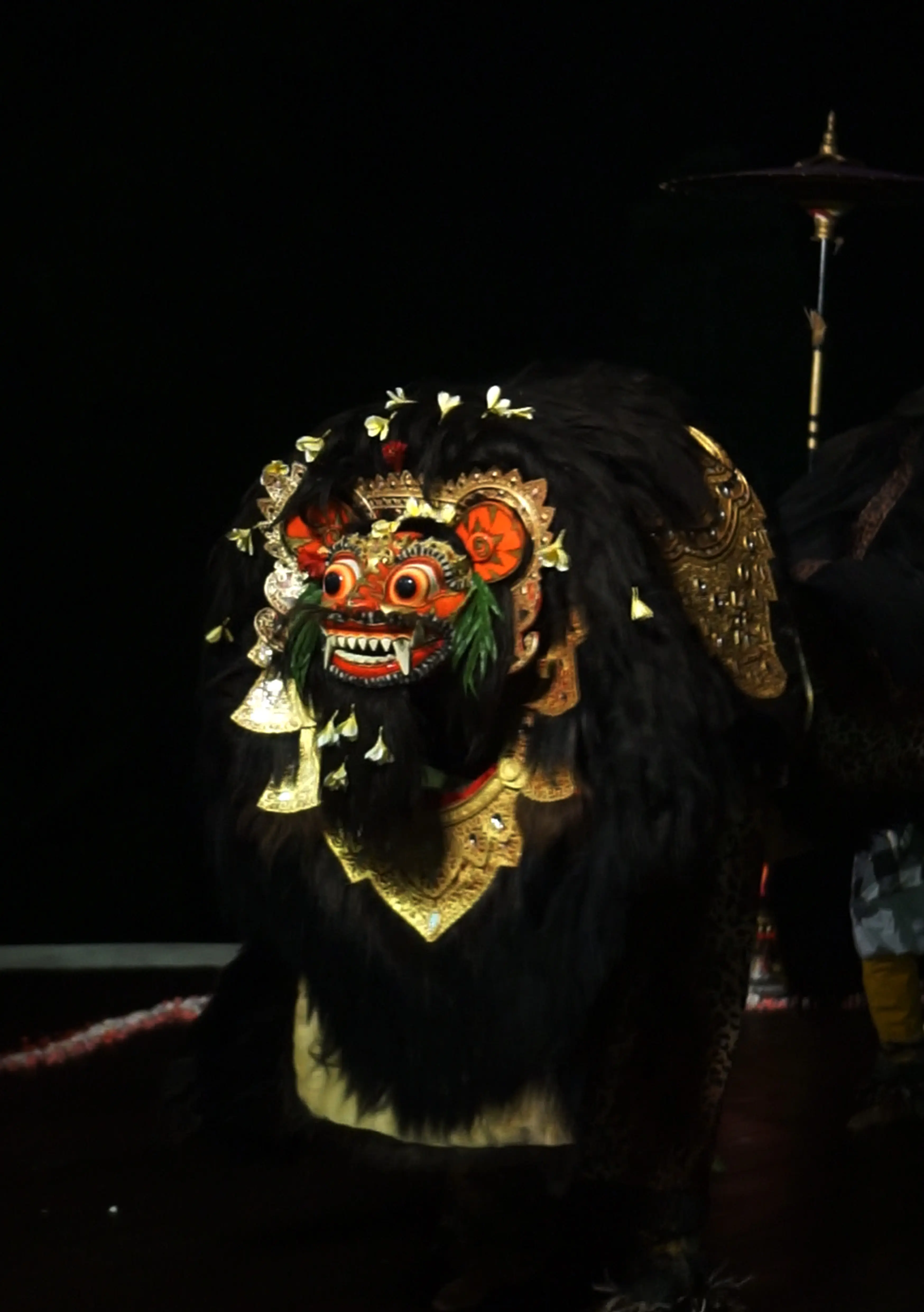 Balinese barong dancers performing at a cultural dinner show in Ubud at Hanging Gardens of Bali, with gamelan music and luxury dining.
